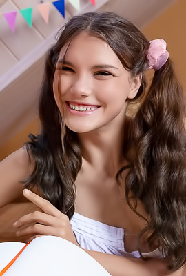 Polina poses nude in a festive bedroom, smiling with pigtails as she teases at her desk by the window
