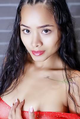 Liloo kneels in red lingerie, teasing with her braids and tattoos, then goes fully nude for sultry bedroom poses